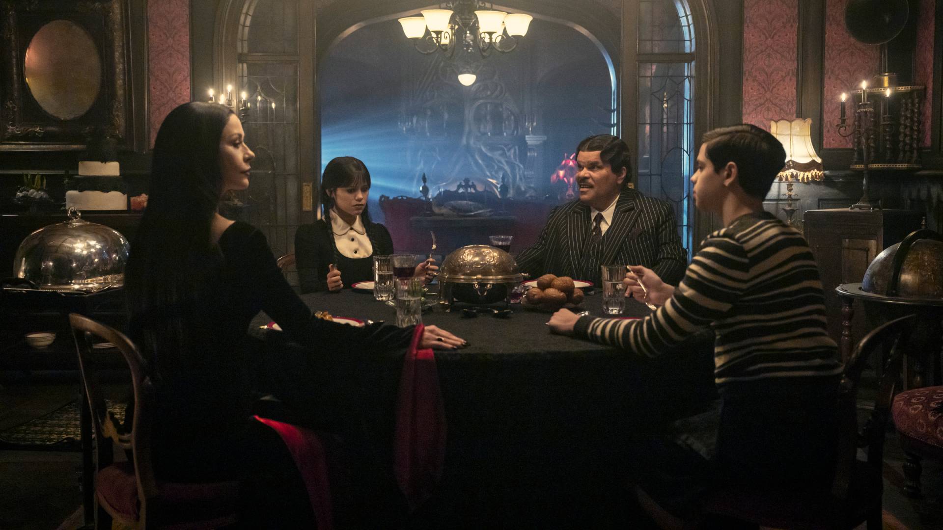 Catherine Zeta-Jones as Morticia Addams, Jenna Ortega as Wednesday Addams, Luis Guzman as Gomez Addams, and Isaac Ordonez as Pugsley Addams in Wednesday season 2 part 2